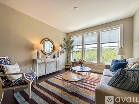 A living room with a sofa, chair, and a table with a vase of flowers on it.