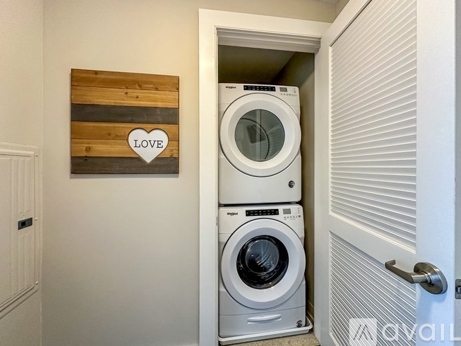 A washing machine is in front of a door with a wooden sign that says love.