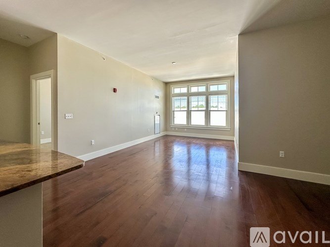A spacious room with wooden floors and a large window.