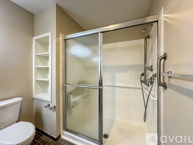 A bathroom with a glass shower door and a toilet.
