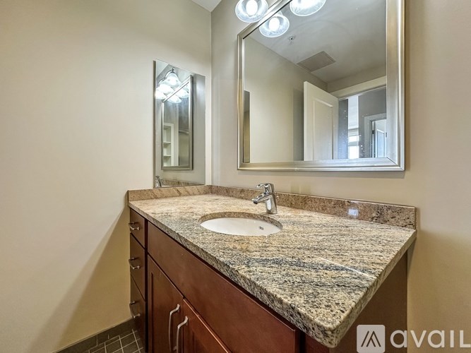 A bathroom vanity with a granite countertop and a large mirror above the sink.