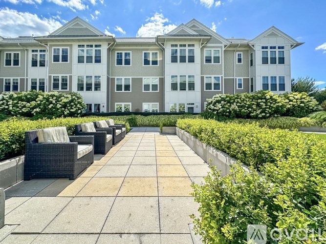 A large, modern building with a spacious front yard and patio furniture.