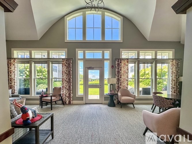 A sunny day outside the window in a room with a sofa and chairs.
