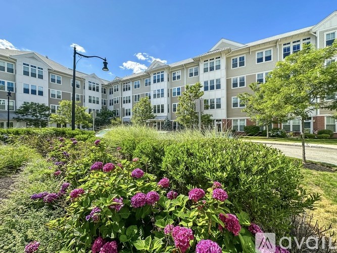 A row of apartment buildings with a flower bed in front.