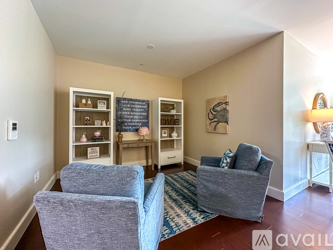 A living room with two grey chairs and a shelf with various items on it.