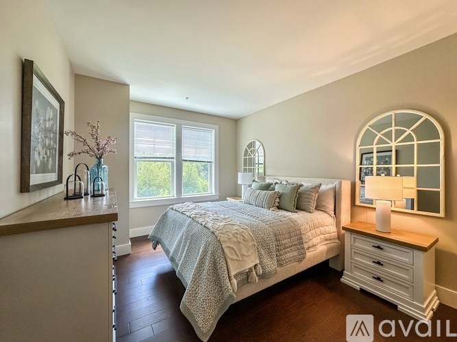 A bedroom with a bed, nightstand, and a window with a view of trees.