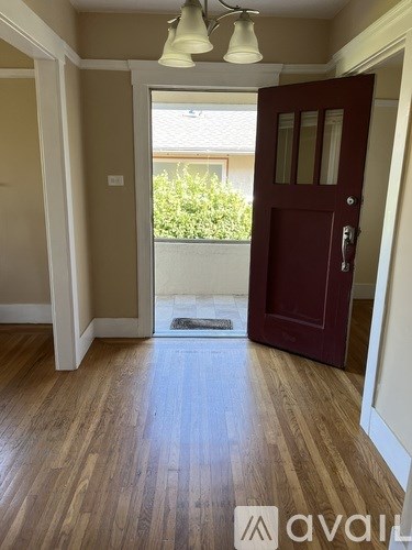 A room with a wooden floor and a red door.