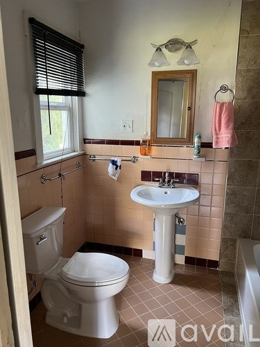 A bathroom with a toilet, sink, and window.