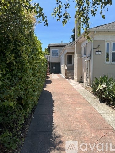 A sidewalk in front of a house with a hedge on the left and a house number 1712 on the right.