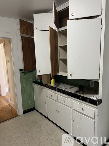 A kitchen with white cabinets and a green backsplash.