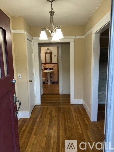 A hallway with a wooden floor and a chandelier.