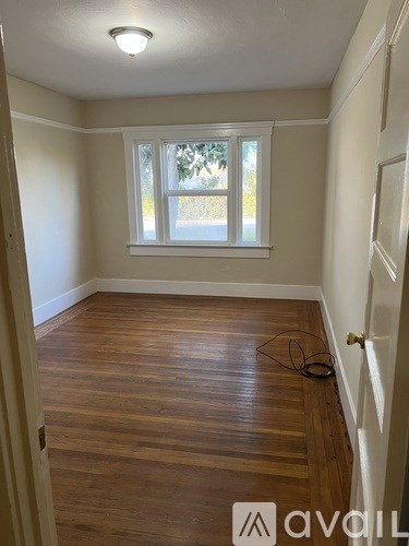A room with wooden flooring and a window.