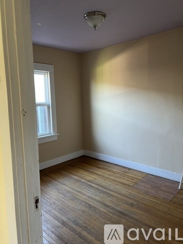 A room with wooden flooring and a window.