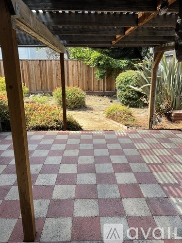 A patio with a checkered floor and a wooden pergola.