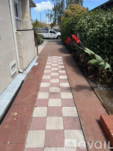 A checkerboard pattern of red and white tiles lines a sidewalk.