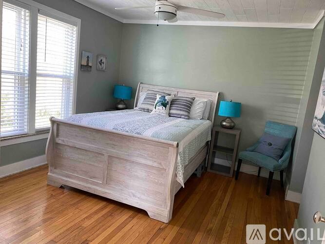 A bedroom with a large bed and a chair.