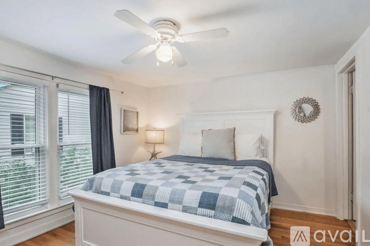 A bedroom with a bed, a ceiling fan, and a window with blinds.