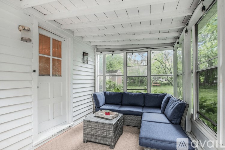 A blue couch is in a sunny room with a white door.