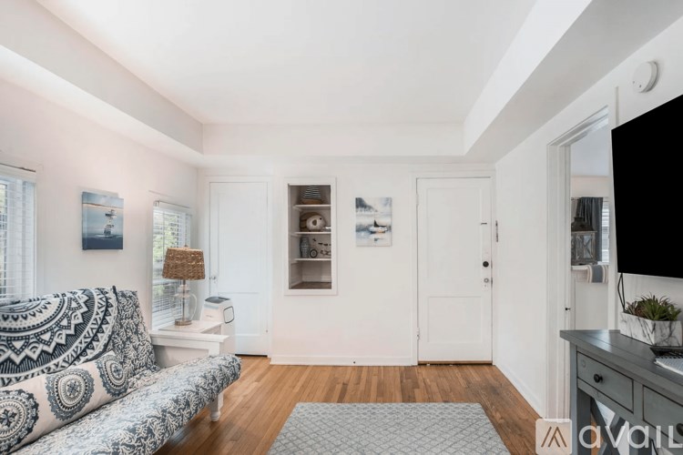 A living room with a couch, a lamp, a television, and a window.