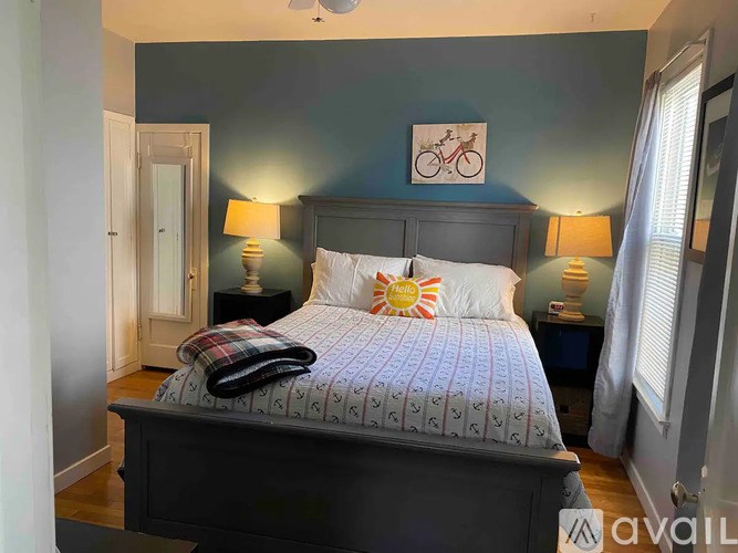 A bedroom with a dark headboard and a bed with a white and grey comforter.