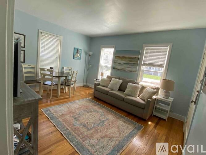 A living room with a couch, chairs, and a rug.