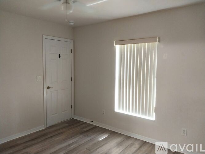 A room with a white door and a window with blinds.