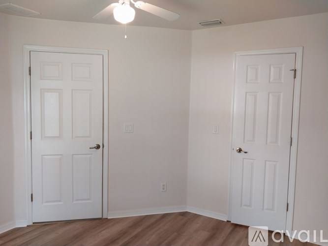 Two white doors in a room with wood floors and a ceiling fan.