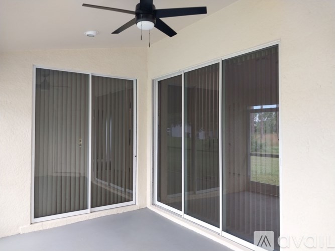 A room with a ceiling fan and sliding glass doors.