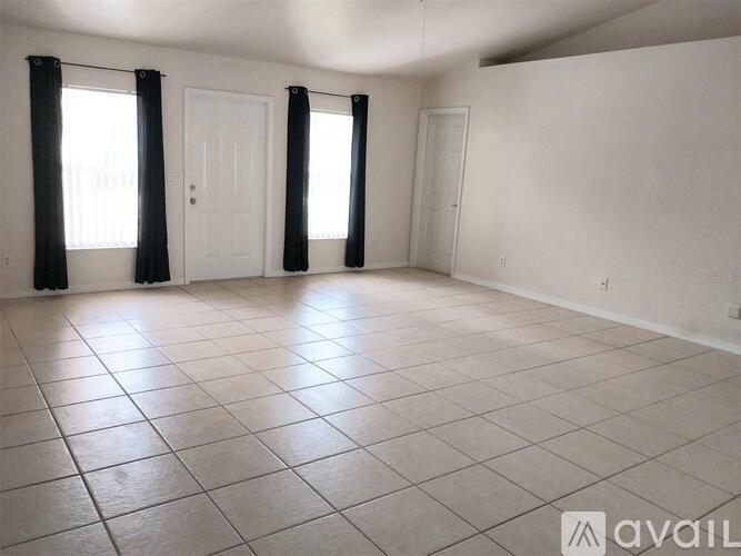 A spacious room with a ceiling fan and tiled flooring.