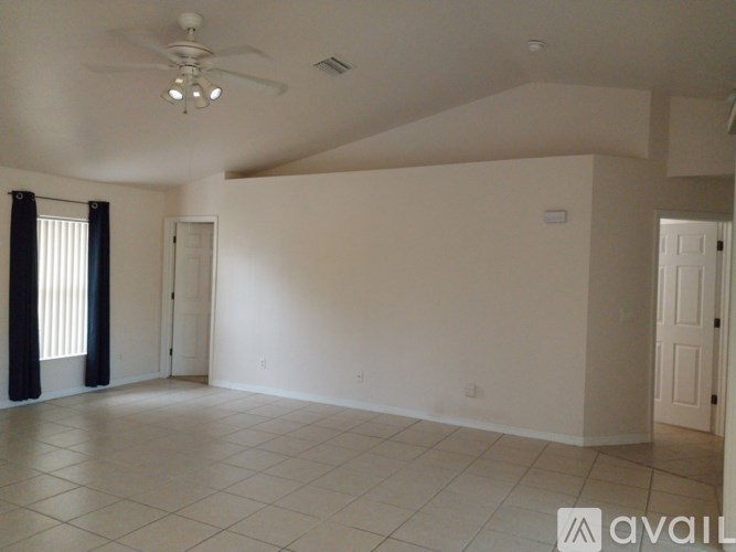 A spacious room with a ceiling fan and tiled flooring.