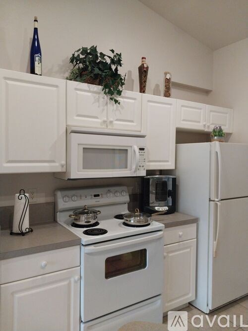 A white kitchen with a stove, microwave, and refrigerator.