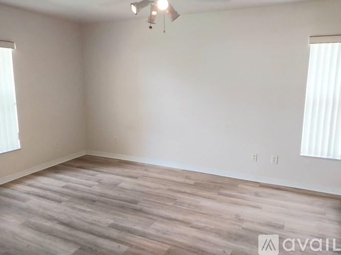 A room with wooden flooring and two windows.