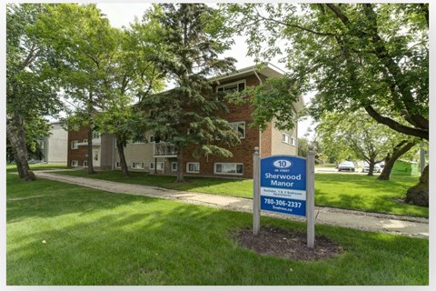 A sign for Sherwood Manor is in the foreground of a grassy area.