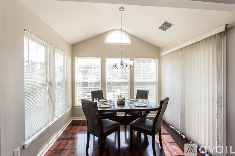 A dining room with a table set for two and a chandelier hanging from the ceiling.
