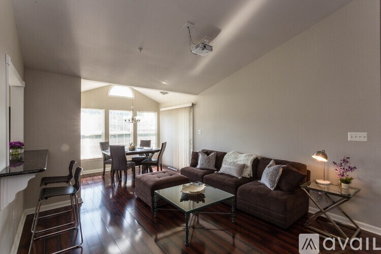 A living room with a brown couch and a glass coffee table.