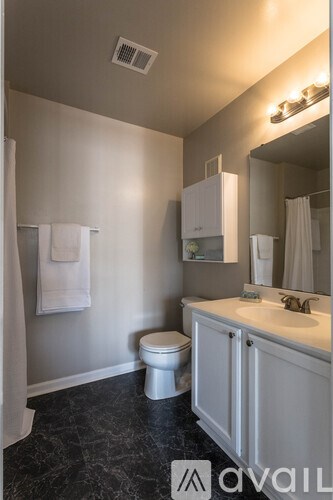 A bathroom with a toilet, sink, and mirror.