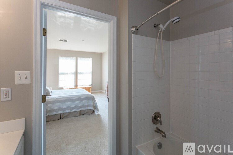 A white bathroom with a shower and a bedroom with a bed.