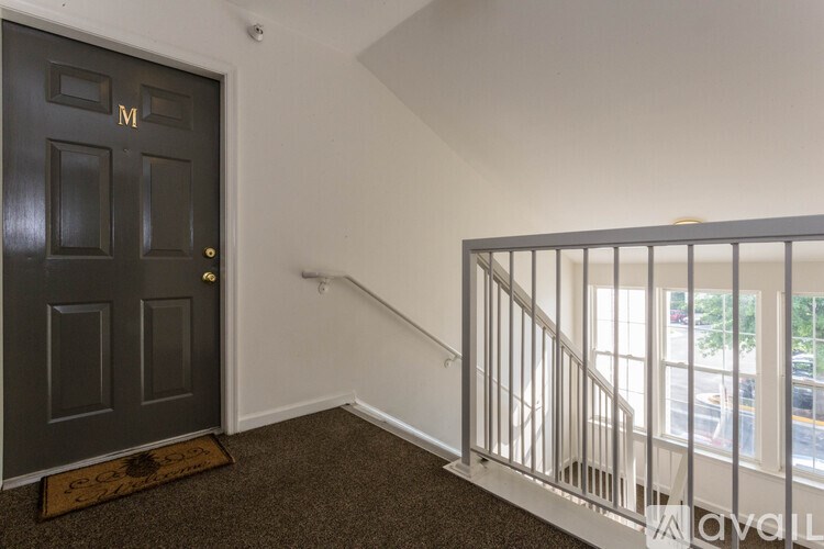 A black door with a gold handle is on the left and a staircase with a metal railing is on the right.