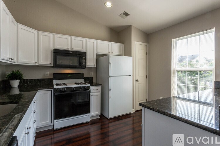 A kitchen with white cabinets and black countertops.