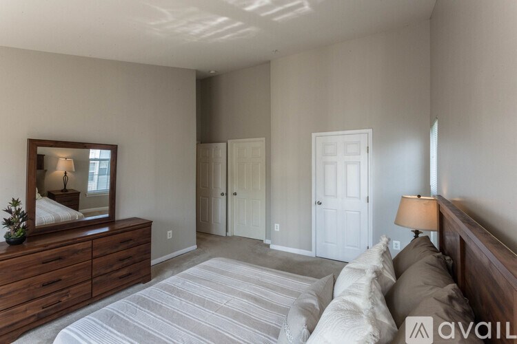 A bedroom with a large bed and a dresser with a mirror above it.