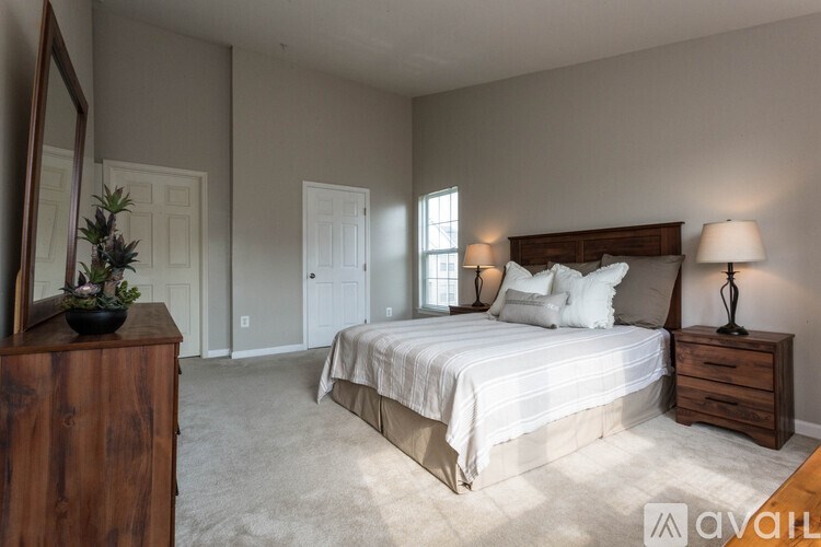 A bedroom with a large bed, a wooden dresser, and a mirror.