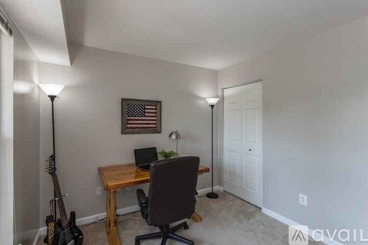 A room with a desk, chair, and guitar.