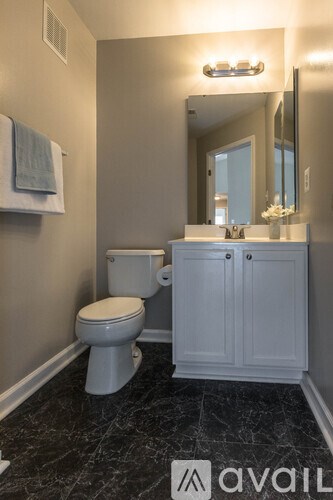 A bathroom with a toilet, sink, and mirror.