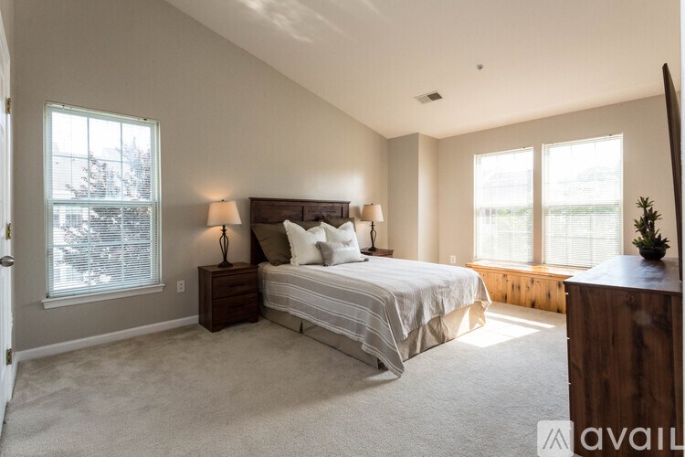 A bedroom with a large bed and a window with blinds.