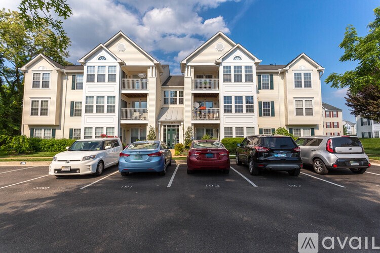 A parking lot in front of a large apartment building with cars parked in designated spaces.
