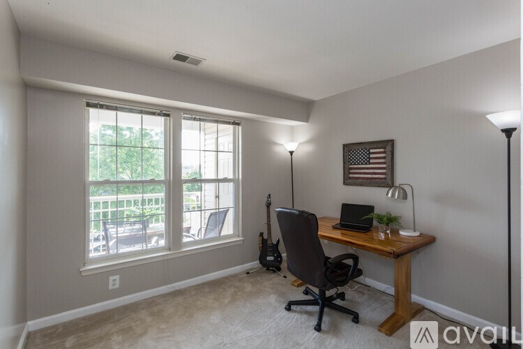 A room with a desk, chair, and guitar.
