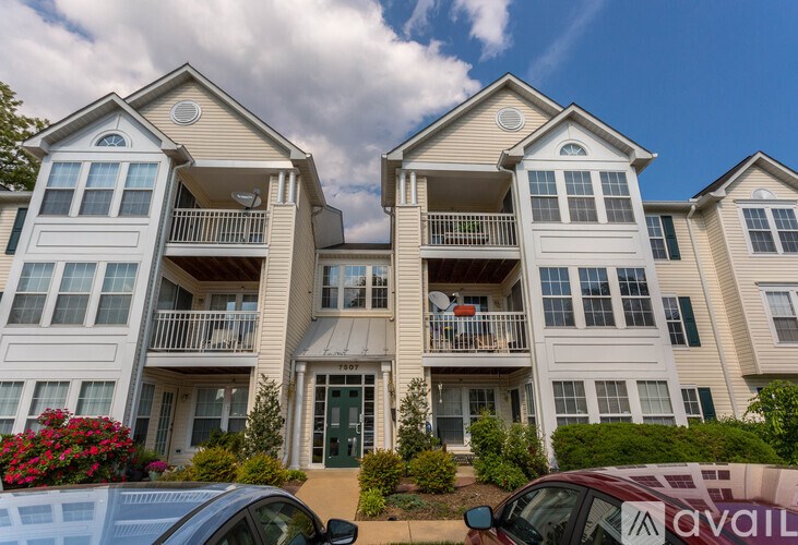 Two identical buildings with balconies and a car parked in front.