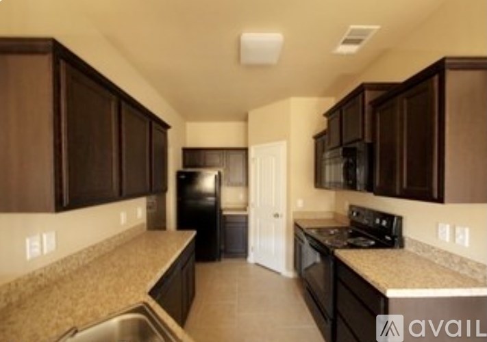 A kitchen with brown cabinets and black appliances.
