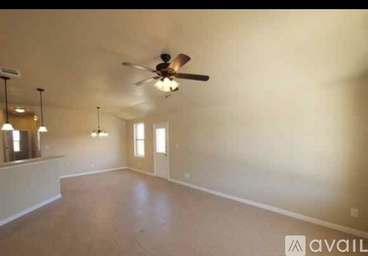 A spacious room with a ceiling fan and two windows.