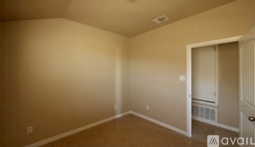 A room with beige walls and a door leading to another room.